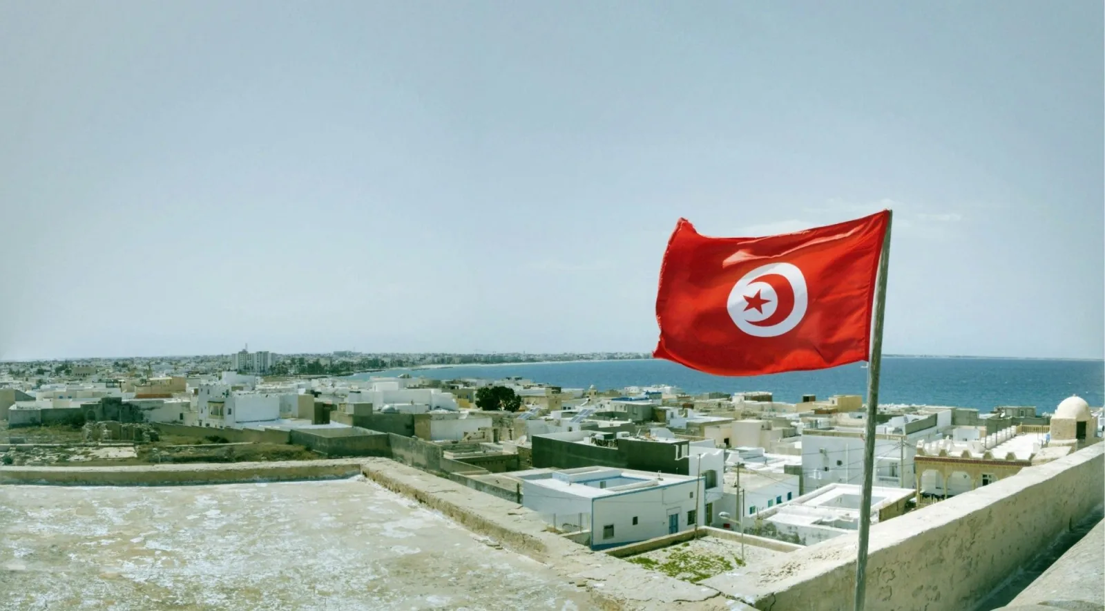 Tunisian flag flying above a whitewashed coastal town