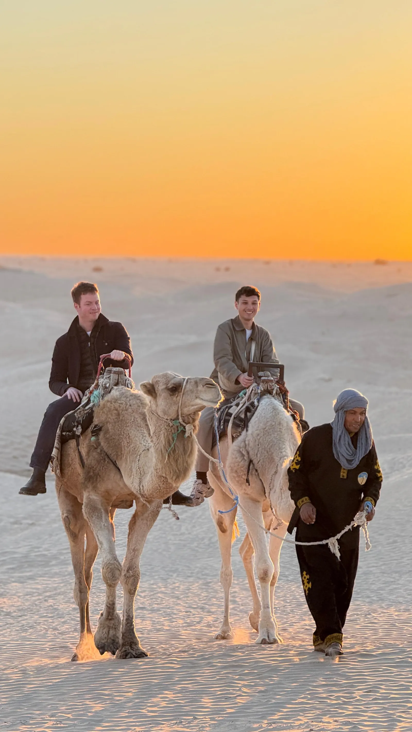 Camel riders led across the dunes by their handler