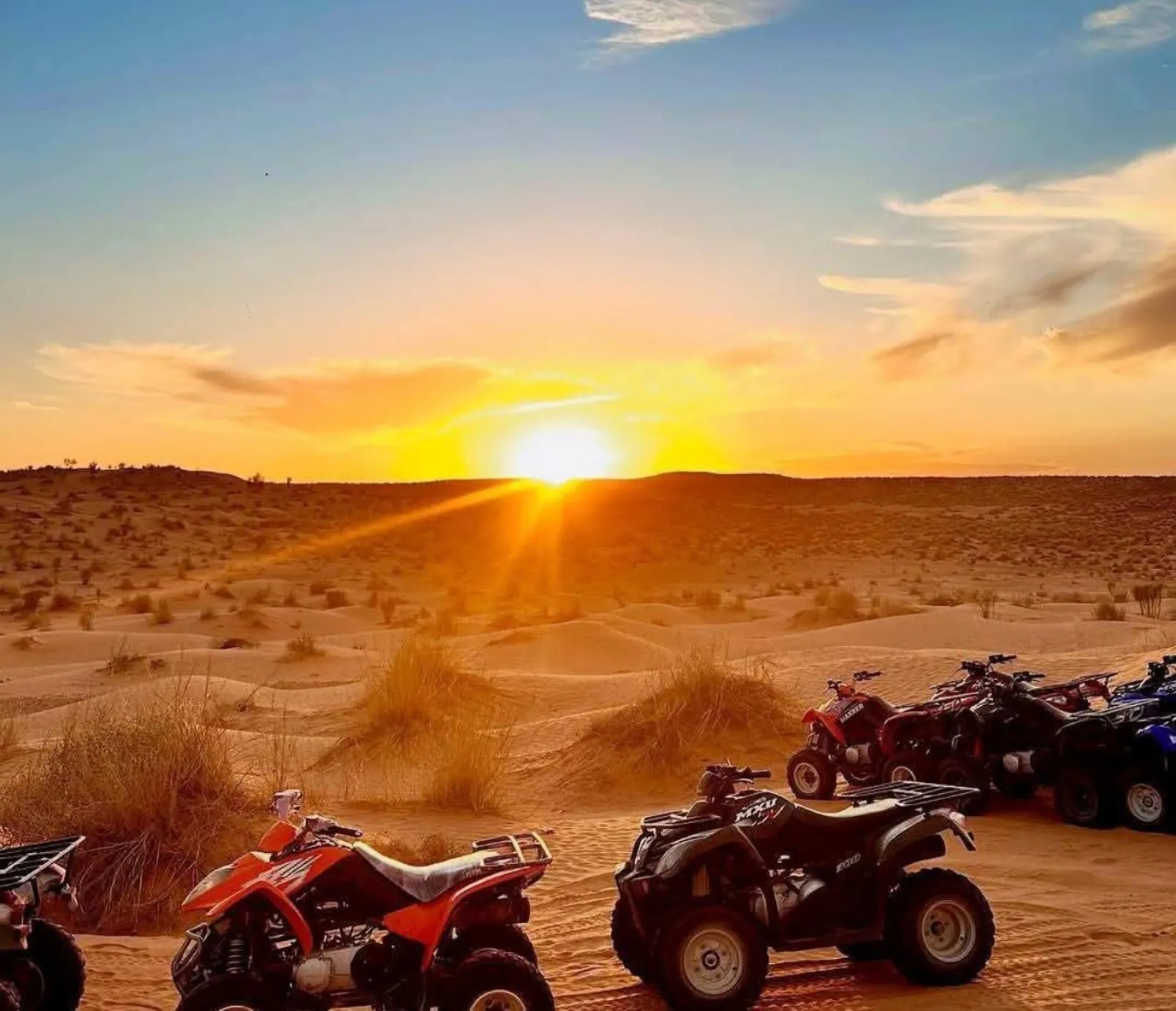 Quad bikes parked on the sand at sunset