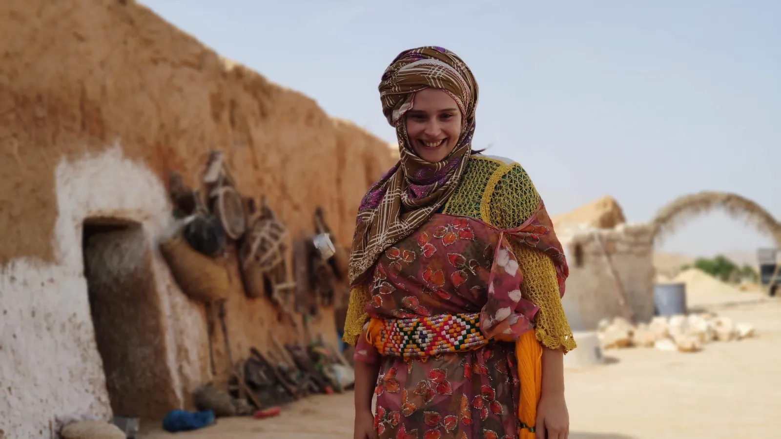 A Berber woman in embroidered dress outside a troglodyte house at Matmata