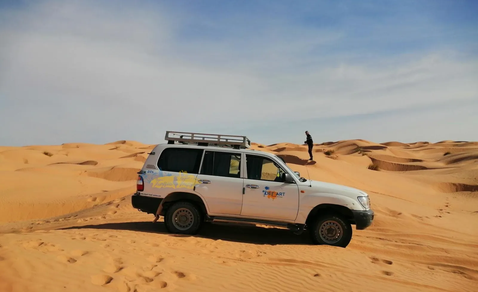 A 4x4 parked on the dunes with open desert beyond