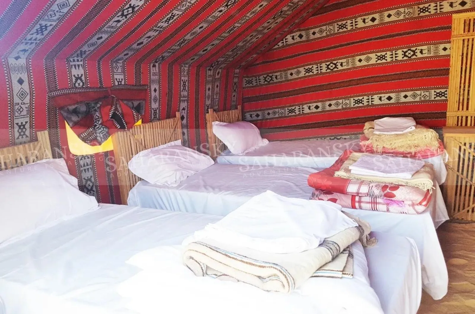 A camp tent interior with woven hangings and made-up beds