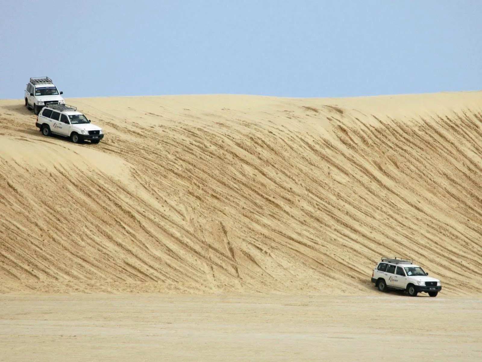 Two 4x4s crossing a dune ridge in the Tunisian Sahara